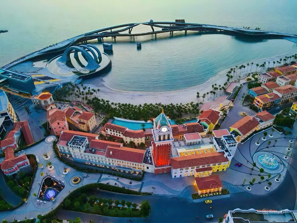 푸꾸옥 선셋 타운(Sunset Town)의 베네치아 스타일 건축물과 인공 해변 및 다리 모습. 화려한 건축물들이 해안가를 따라 늘어서 있습니다. 푸꾸옥 숙소 싸게 정보를 찾을 때 참고할 수 있는 관광지 근처 숙소 옵션입니다.