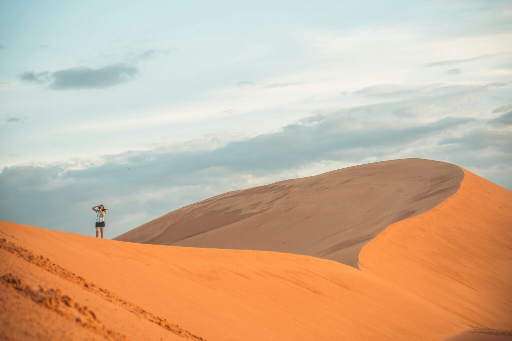 무이네 당일치기로 방문한 여행자가 붉은 모래 언덕(Red Sand Dune)의 능선 위에 서서 일몰을 감상하고 있는 모습. 광활하고 고요한 사막 풍경이 인상적입니다.