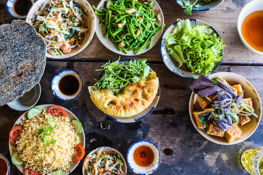 나트랑에서 맛보는 다양한 베트남 로컬 음식과 길거리 음식. 중앙에 신선한 채소와 함께 있는 반쎄오(Bánh Xèo, 베트남식 부침개)가 돋보이는 식탁.