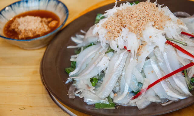 베트남 무이네의 대표적인 해산물 요리인 '까 마이(Gỏi Cá Mai, 생선 샐러드)' 클로즈업 사진입니다. 얇게 썬 생선회와 채소, 땅콩 가루가 곁들여져 있으며, 무이네 여행 중 꼭 맛봐야 할 현지 음식을 보여줍니다.